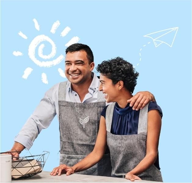 Two smiling men in grey aprons, one with his arm around the other, against a light blue background with a drawn sun and paper airplane.